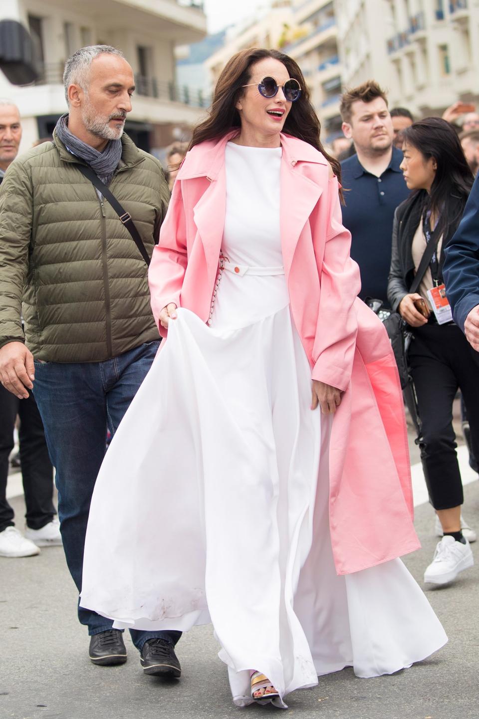 Andie MacDowell exudes effortless style in a chic long white dress, paired with a bright pink coat while out and about at the festival.