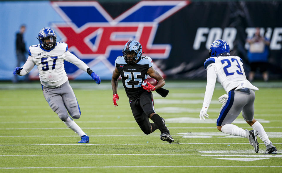 Dallas Renegades running back Lance Dunbar (25) carries the ball as St. Louis Battlehawks linebacker Terence Garvin (57) and safety Kenny Robinson (23) defend during an XFL football game against the St. Louis Battlehawks, Sunday, Feb. 9, 2020, in Arlington, Texas. St. Louis won 15-9. (AP Photo/Brandon Wade)