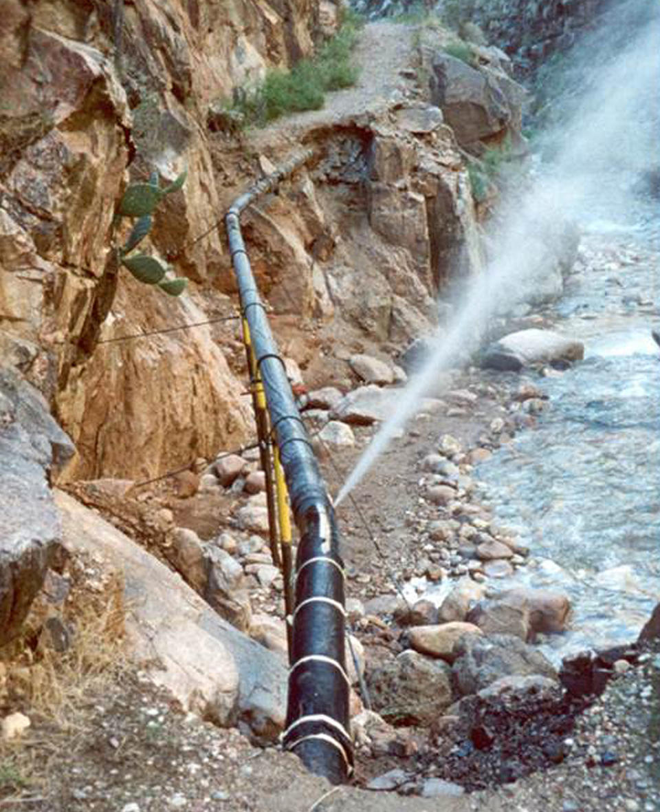 FILE - This undated photo provided by the National Park Service shows water spraying from a break in an exposed section of the Grand Canyon trans-canyon waterline, originally covered under a path, after a flash flood event. Work has begun on giving some of America’s most spectacular natural settings and historic icons a makeover. (National Park Service via AP, File)