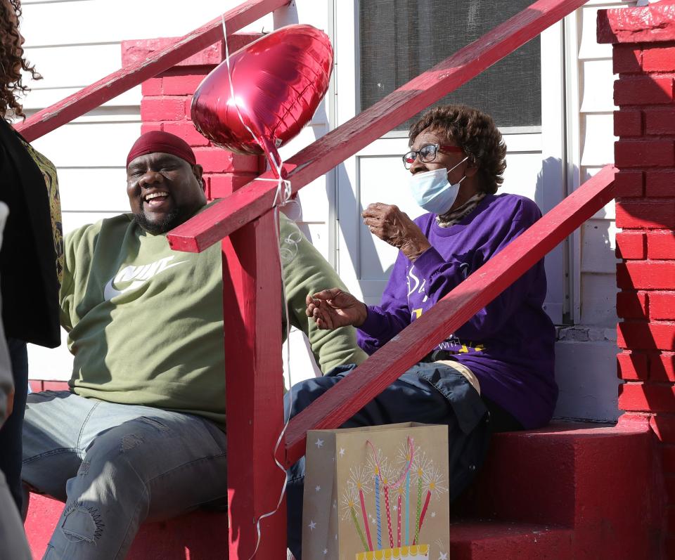 Earlene Fullwood, right, and her grandson, Aaron Jones, left, share a laugh with visitors Sunday, Feb. 11, 2024, during a drive-by 100th birthday celebration in front of Fullwood's East Summit Street home in Alliance.