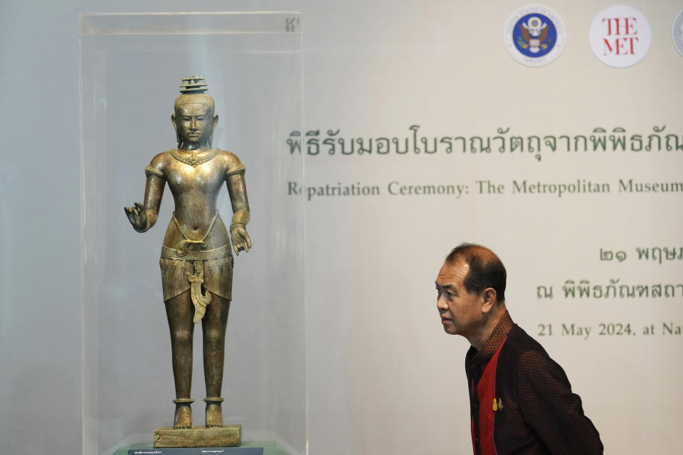 Thai person looks at a standing Shiva sculpture from the 11th century during repatriation ceremony at National Museum in Bangkok, Thailand, Tuesday, May 21, 2024. Thailand's National Museum hosted a welcome-home ceremony Tuesday for two ancient statues that were illegally trafficked from Thailand by a British collector of antiquities and were returned from the collection of New York’s Metropolitan Museum of Art. (AP Photo/Sakchai Lalit)