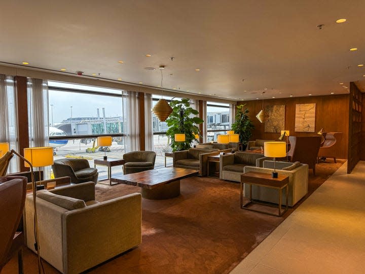 A sleek seating area is shown at Cathay Pacific's The Pier, a first- class lounge at Hong Kong International Airport. Low chairs and tables and soft lighting fills the space.