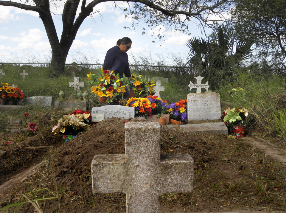 Cecilia Hernandez lleva flores las tumbas de sus familiares en el cementerio Santa Rosalía (Nathan Lambrecht/The Monitor via AP)