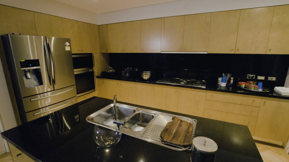 Stainless steel appliances contrast the timber finish of the storage spaces