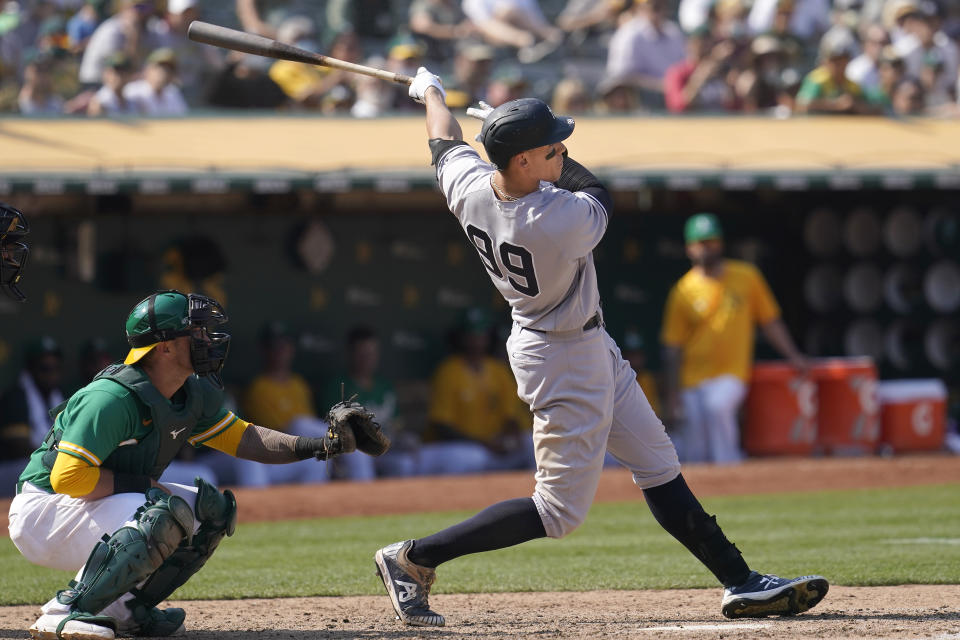 New York Yankees' Aaron Judge (99) hits a two-run home run in front of Oakland Athletics catcher Yan Gomes during the ninth inning of a baseball game in Oakland, Calif., Saturday, Aug. 28, 2021. (AP Photo/Jeff Chiu)