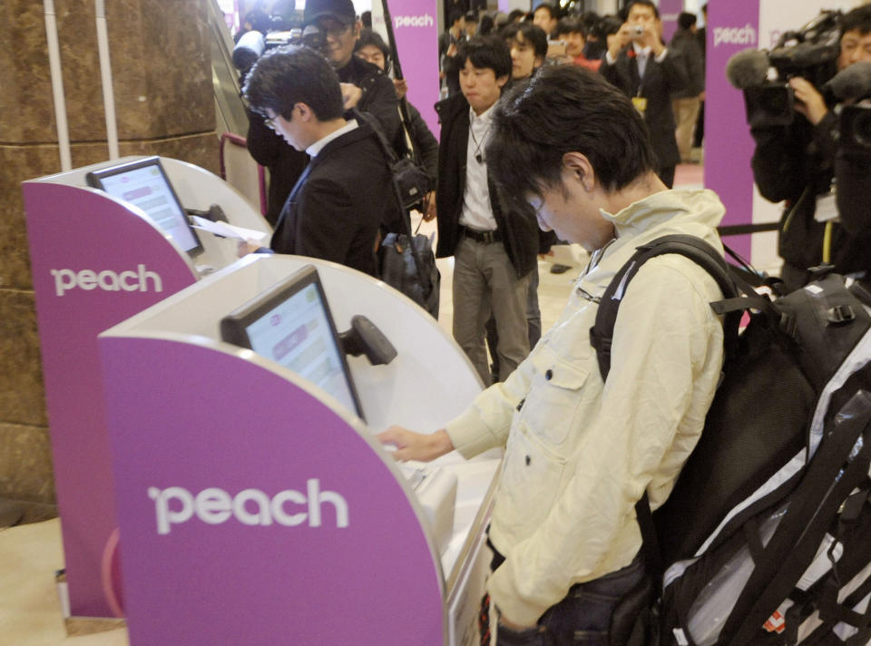 In this March 1, 2012 photo, passengers use self-service check-in kiosks to board the first flight by Peach Aviation at Kansai Airport in Osaka, western Japan. Japan has a reputation for loving expensive things like overpriced real estate, gourmet melons and luxury brands. But the nation is finally discovering the joy of flying cheap, with the arrival this year of three low-cost carriers. The takeoff of AirAsia Japan, Peach Aviation and Jetstar Japan could change lifestyles. (AP Photo/Kyodo News) JAPAN OUT, MANDATORY CREDIT, NO LICENSING IN CHINA, FRANCE, HONG KONG, JAPAN AND SOUTH KOREA