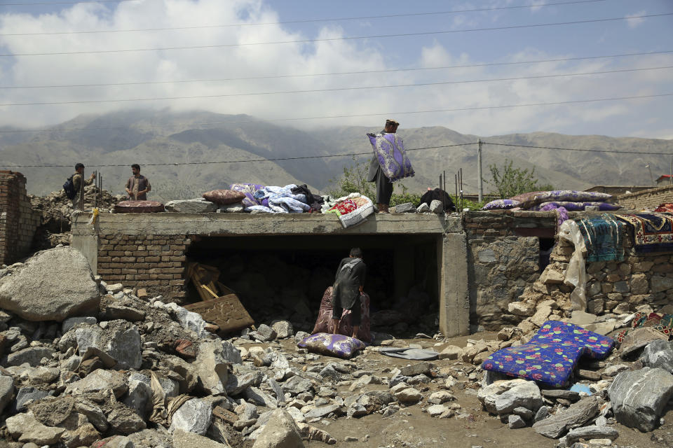 Afghans salvage belongings from their house that was damaged in a mudslide caused by flooding in the Parwan province, north of Kabul, Afghanistan, Thursday, Aug. 27, 2020. The death toll from heavy flooding in northern and eastern Afghanistan rose to at least 150 on Thursday, with scores more injured as rescue crews searched for survivors beneath the mud and rubble of collapsed houses, officials said. (AP Photo/Rahmat Gul)