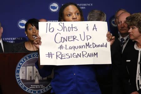 A protester against Chicago Mayor Rahm Emanuel (not pictured) stands in front of U.S. Conference of Mayors President Baltimore Mayor Stephanie Rawlings-Blake (at podium) at the opening press conference of the U.S. Conference of Mayors in Washington January 20, 2016. REUTERS/Gary Cameron