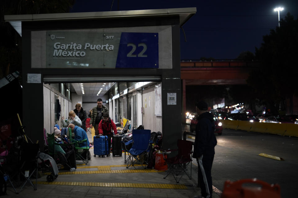 FILE - Ukrainian refugees wait in a bus stop near the border Monday, April 4, 2022, in Tijuana, Mexico. As many as 20,000 Ukrainians who were granted permission to remain in the United States for one year after fleeing the early fighting in their native country are facing their humanitarian parole expiring, according to advocates. (AP Photo/Gregory Bull, File)