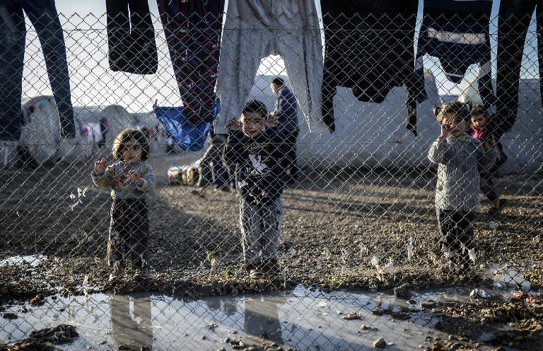 Syrian children stand behind a fence at the Rojava refugee camp in Turkey, on February 1, 2015