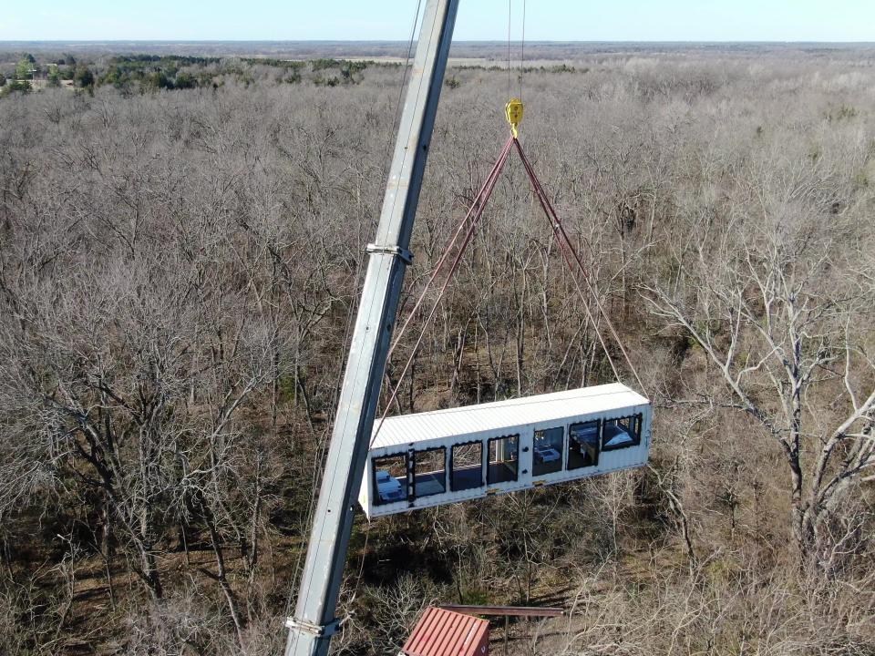 A crane lowering one of the shipping containers onto the ground.