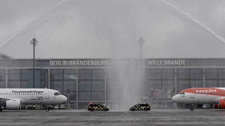 Petrus ist auch nicht gerade in Festivalstimmung: Flugzeuge der Fluggesellschaften Lufthansa und Easyjet stehen nach der Landung unter einer Wasserfontäne der Flughafen-Feuerwehr am BER - es regnet und der Himmel ist grau verhangen. Foto: dpa