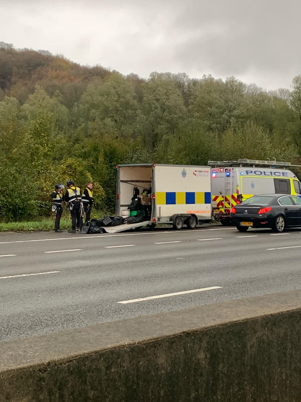 Handout photo taken with permission from the twitter account @SurreyPolice of officers preparing to remove a Just Stop Oil protester who has climbed a gantry on the M25 between junctions six and seven in Surrey, leading to the closure of the motorway. Surrey Police said the decision was made to close the road 