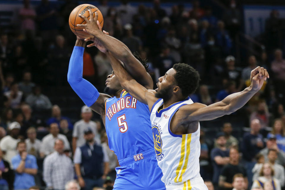 Oklahoma City Thunder forward Luguentz Dort (5) grabs a rebound next to Golden State Warriors forward Andrew Wiggins (22) in the first half of an NBA basketball game Tuesday, Oct. 26, 2021, in Oklahoma City. (AP Photo/Nate Billings)