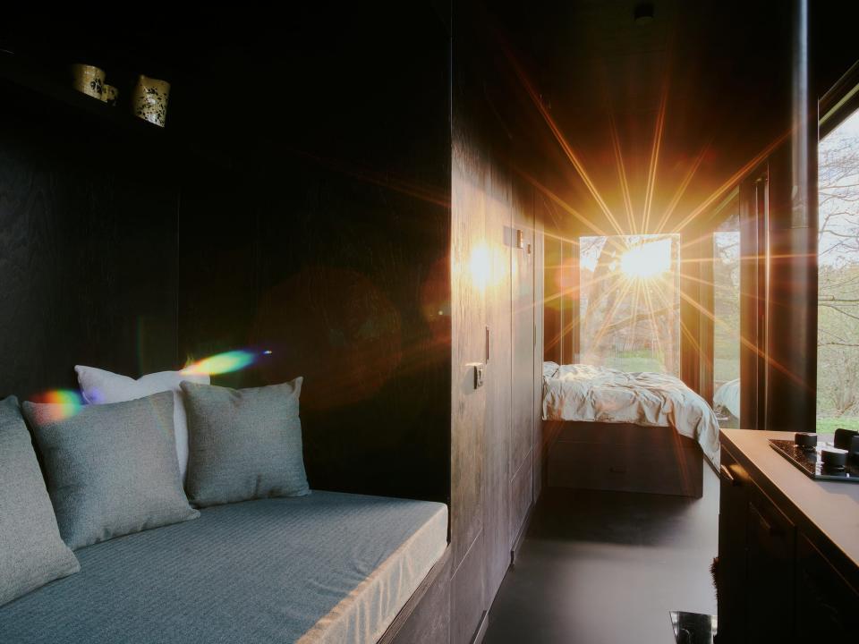 Sun shining through the window in a Raus cabin with a daybed, bed.
