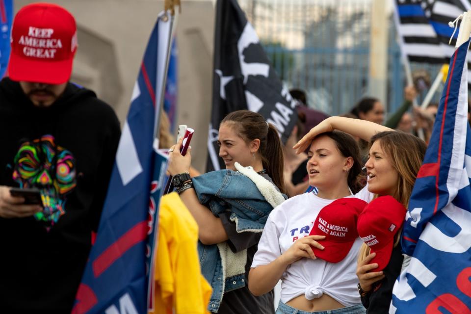 Young people with red hats bearing the words Make America Great Again gather near flags