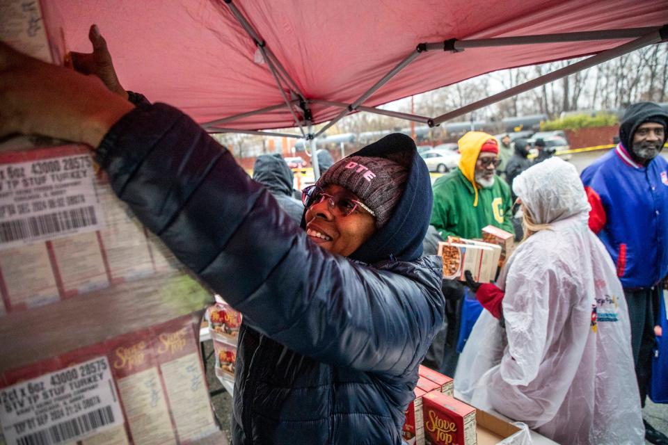 Lovie Wilson, 49, of Belleville reaches for boxes of food she helps hand out, while volunteering with DTE Energy, where she works, during the annual Thanksgiving All-Star Giveback at River Rouge High School in River Rouge, Mich. on Tuesday, Nov. 21, 2023.