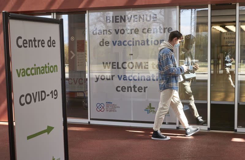 A man walks past a sign at a COVID-19 vaccination center at the Palexpo in Geneva