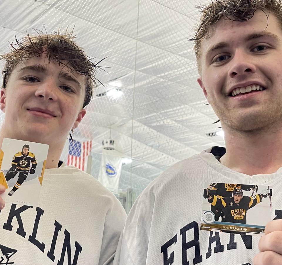 Franklin seniors Dylan McEvoy, left, and Logan Marchand hold hockey cards of their Boston Bruins namesakes, Charlie McEvoy and Brad Marchand, after practice at Pirelli Veterans Arena in Franklin on March 4, 2024.