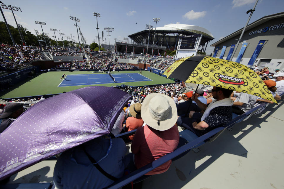 Fans use umbrellas to shelter from the sun as they watch the match between Victoria Azarenka, of Belarus, and Daria Gavrilova, of Australia, during the second round of the U.S. Open tennis tournament, Wednesday, Aug. 29, 2018, in New York. (AP Photo/Frank Franklin II)