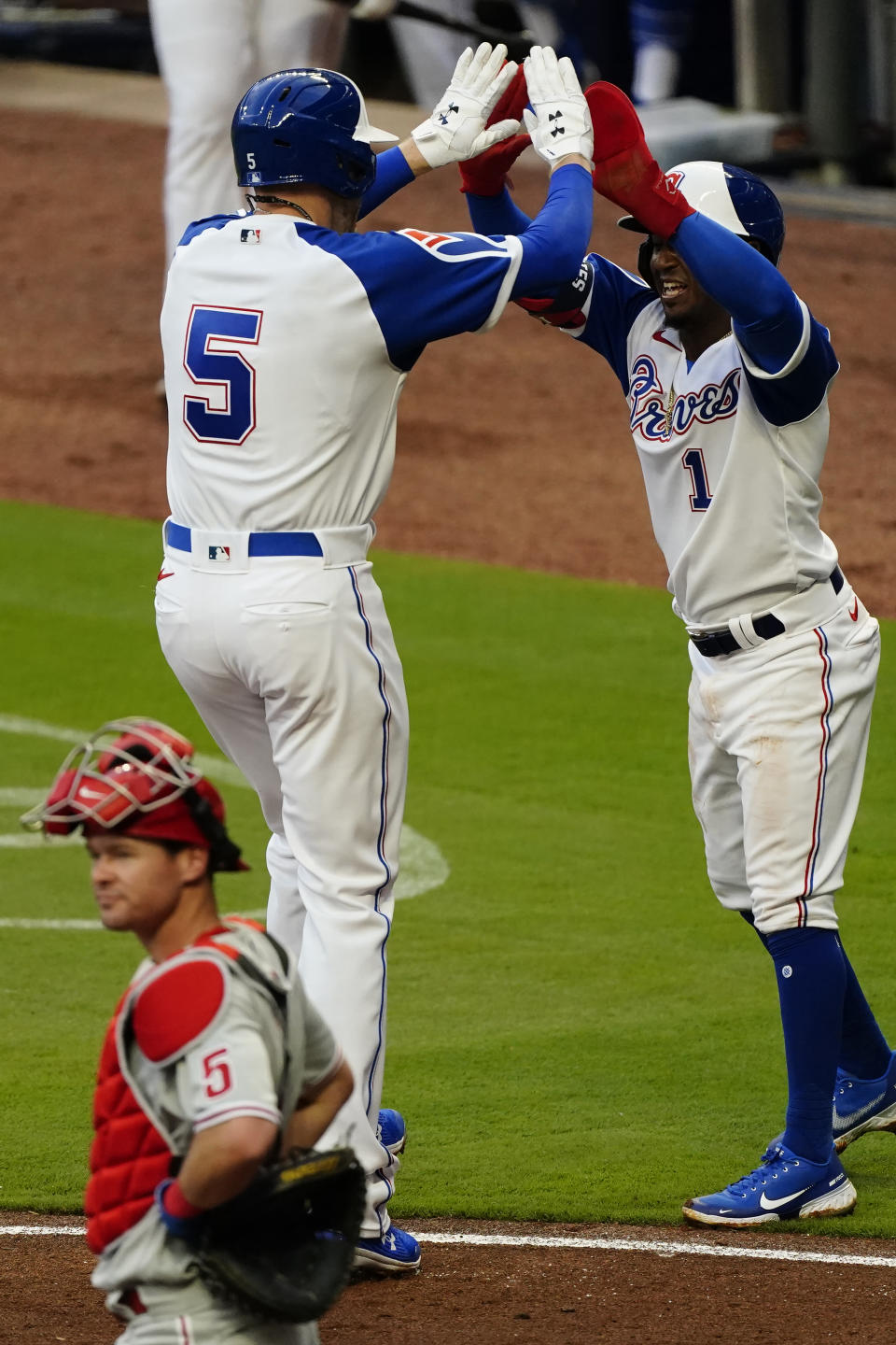 Atlanta Braves' Freddie Freeman (5) celebrates with Ozzie Albies after hitting a two-run home run in the first inning of a baseball game against the Philadelphia Phillies, Saturday, April 10, 2021, in Atlanta. Phillies catcher Andrew Knapp (5) looks on. (AP Photo/John Bazemore)