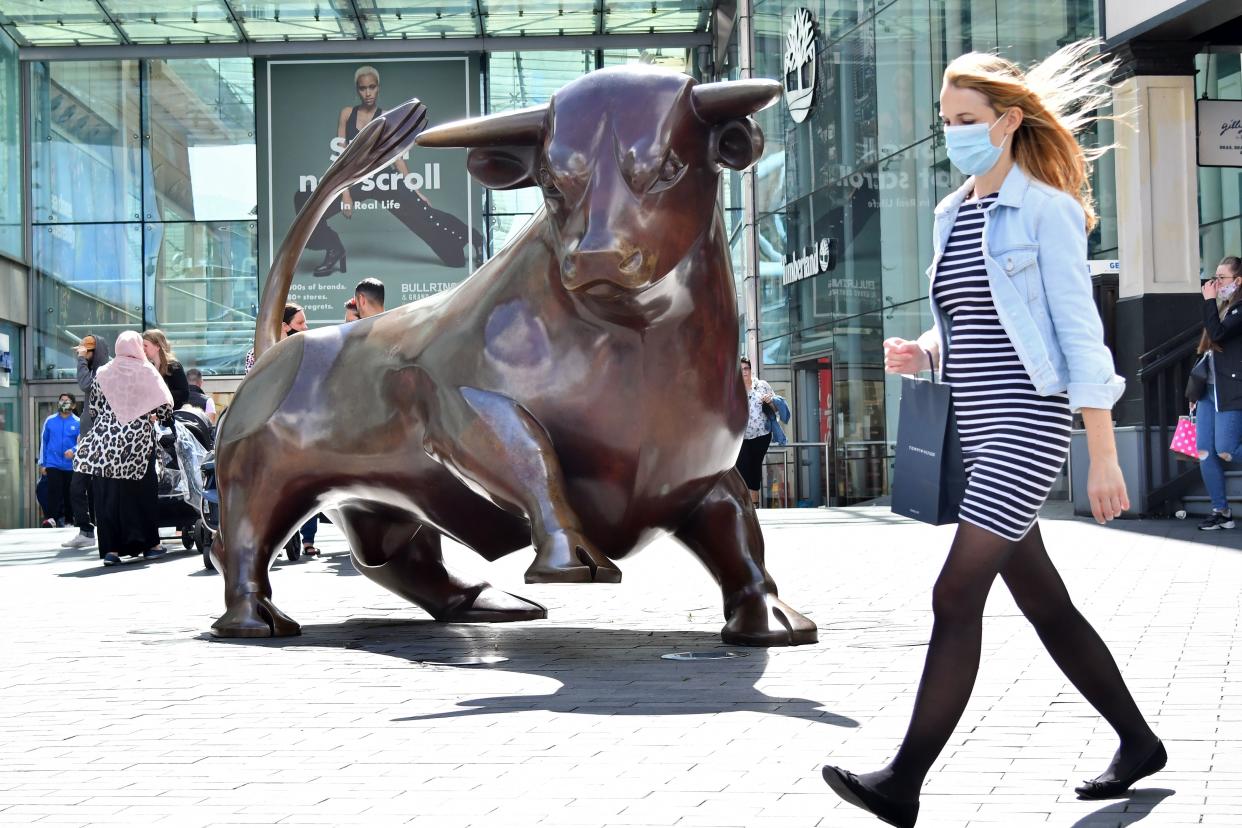 A shopper wearing a protective face mask walks past the Bull statue outside the Bullring shopping centre in Birmingham, central England on August 22, 2020, as Britain's second-city, home to more than one million people, was made an "area of enhanced support", because of concern about a spike in cases of the novel coronavirus. (Photo by JUSTIN TALLIS / AFP) (Photo by JUSTIN TALLIS/AFP via Getty Images)
