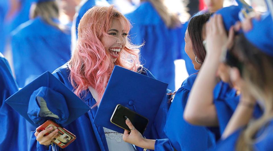 Isabel Ahumada Pedraza shares a laugh with friends during Quincy High School's graduation at Veterans Stadium on Tuesday, June 7, 2022.