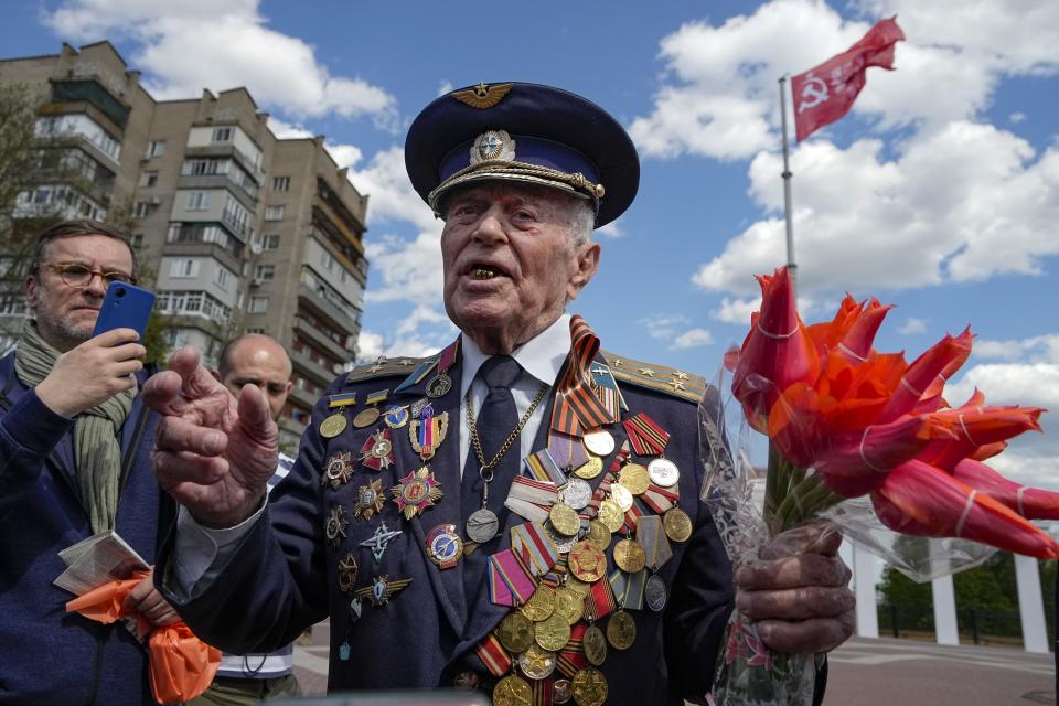 FILE - Vladimir Kapitonovin, 98, a WWII veteran and former military pilot, gestures while speaking to a group of foreign journalists with a red flag, a replica of the Victory banner in Melitopol, Zaporizhzhia region, in territory under Russian military control, southeastern Ukraine, May 1, 2022. The defeat of Nazi Germany in World War II that Russia celebrates on May 9 is the country's most important holiday. This year it has special meaning amid the war in Ukraine, which the Kremlin calls a "special military operation" aimed to rid the country of alleged "neo-Nazis" — a false accusation derided by the West. (AP Photo/Alexander Zemlianichenko, File)