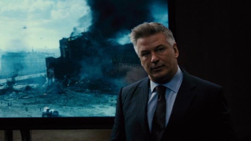 Alec Baldwin in front of an image of a destroyed Kremlin  in Mission: Impossible - Rogue Nation