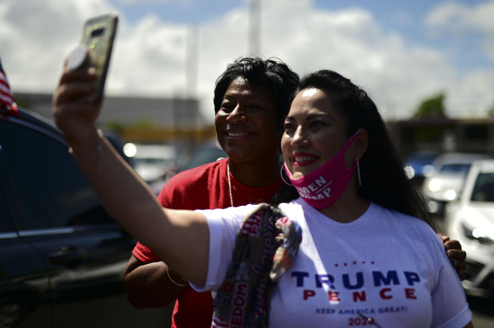 (From the left) conservative senator Nayda Venegas and Frances Lee, supporters of president Donald Trump, pose for a selfie moments before leaving for the headquarters of the Republican party in support of his candidacy a few weeks before the presidential election next November, in Carolina, Puerto Rico, Sunday, Oct. 18, 2020. President Donald Trump and former Vice President Joe Biden are targeting Puerto Rico in a way never seen before to gather the attention of tens of thousands of potential voters in the battleground state of Florida. (AP Photo/Carlos Giusti)