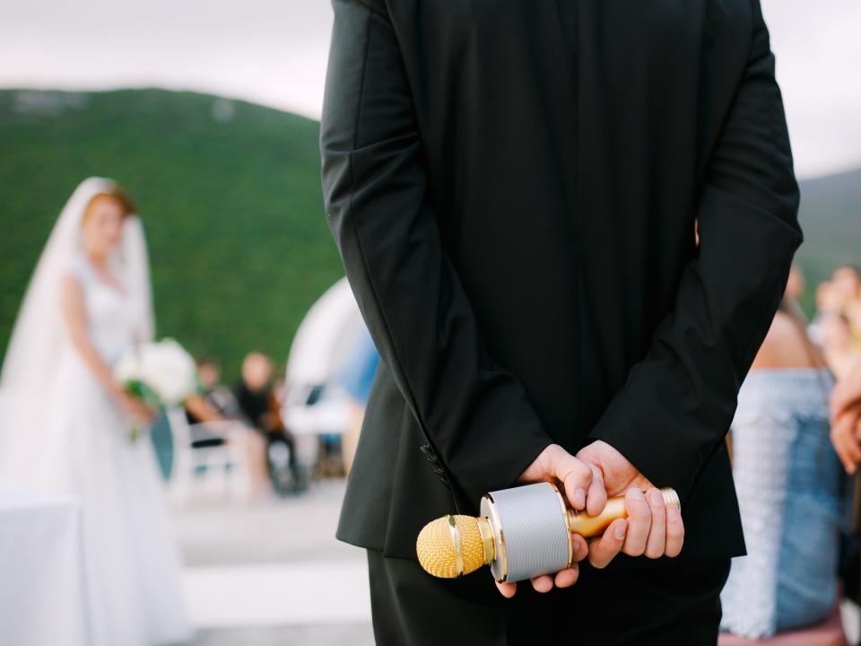 a person at a wedding holding a gold microphone behind their back