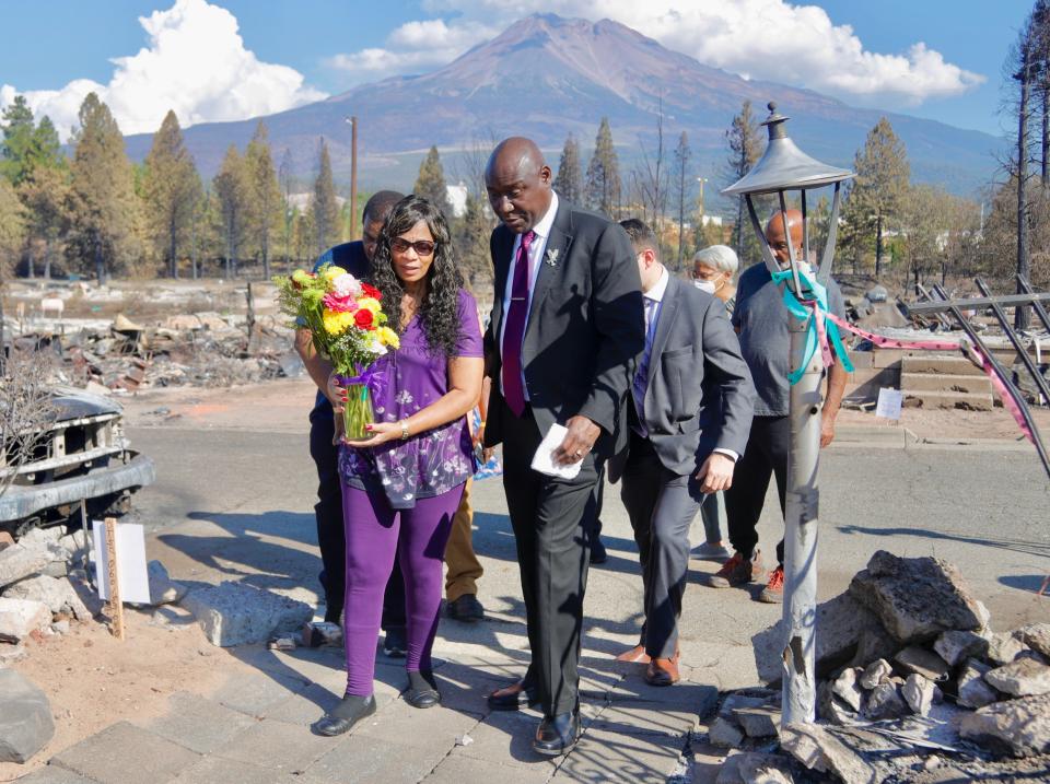 Blenda Clark Long, left, walks with civil rights attorney Ben Crump on Sept. 16 as they go to the burned-down home of Long's aunt, Marilyn Hilliard, so Clark can lay flowers there. Hilliard died in the Sept. 2 Mill Fire and Long's uncle, Clardies Hilliard, suffered burns.