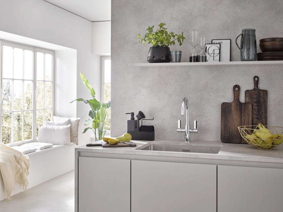 A kitchen with a grey countertop and chrome mixer tap