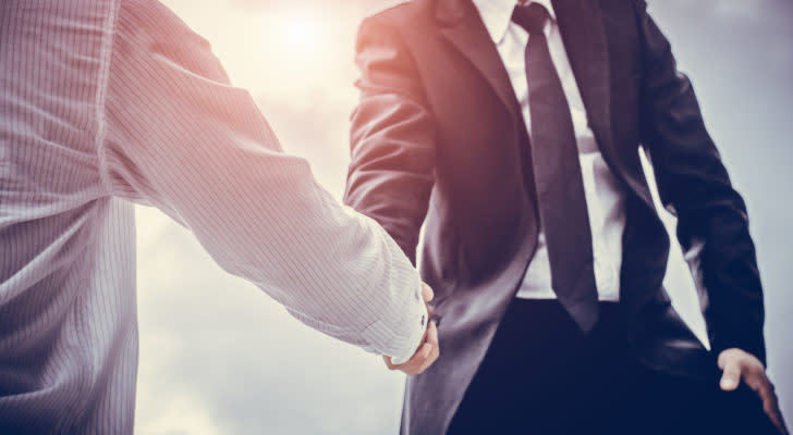 Two business men shaking hands in a sunny setting