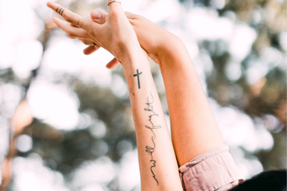 Wrist cross tattoo with accompanying script <p>Unsplash</p>