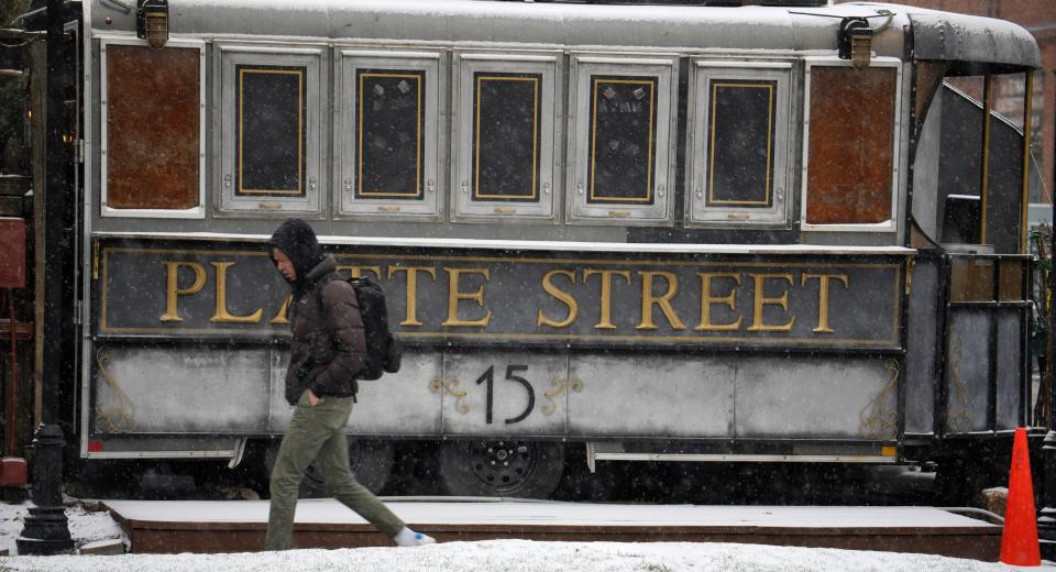 A pedestrian walks along Platte Street as a light snow from a spring storm swept over the intermountain West Tuesday, April 4, 2023, in Denver. Forecasters predict that the storm will move out of the region on Tuesday and over the northern plains states where some locations could see up to two feet of snow.