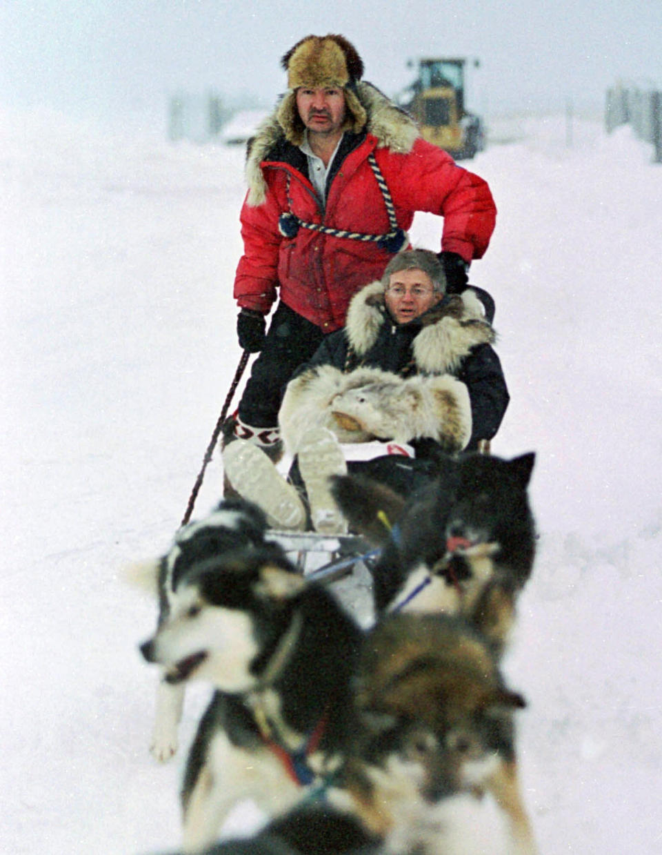 FILE - In this Jan. 19, 2000 file photo, U.S. Census Bureau director Kenneth Prewitt, seated, gets a dog sled ride into town by Harold Johnson after arriving for the first count in the Eskimo village of Unalakleet, Alaska. The 2020 Census kicks off Tuesday, Jan. 21, 2020, in a remote town of Alaska. To mark the occasion, The Associated Press is republishing an article from 20 years ago, when the census began in the village of Unalakleet. (AP Photo/Al Grillo, File)