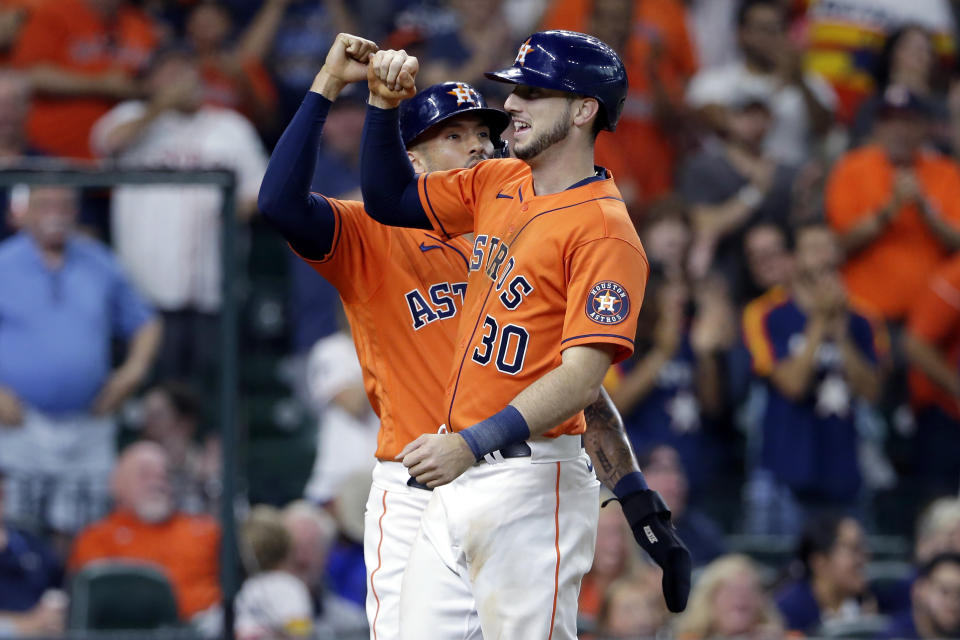 Houston Astros shortstop Carlos Correa, left, and Kyle Tucker (30) celebrate after they scored on Tucker's three-run home run against the Texas Rangers during the third inning of a baseball game Friday, July 23, 2021, in Houston. (AP Photo/Michael Wyke)