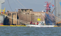 Relatives of missing passengers of the sunken Sewol ferry on a boat, front, watch its salvage operation in waters off Jindo, South Korea, Thursday, March 23, 2017. South Korean workers on Thursday slowly pulled up the 6,800-ton ferry from the water, nearly three years after it capsized and sank into the violent seas off South Korea's southwestern coast, an emotional moment for a country that continues to search for closure to one of its deadliest disasters ever.(Kyodo News via AP)