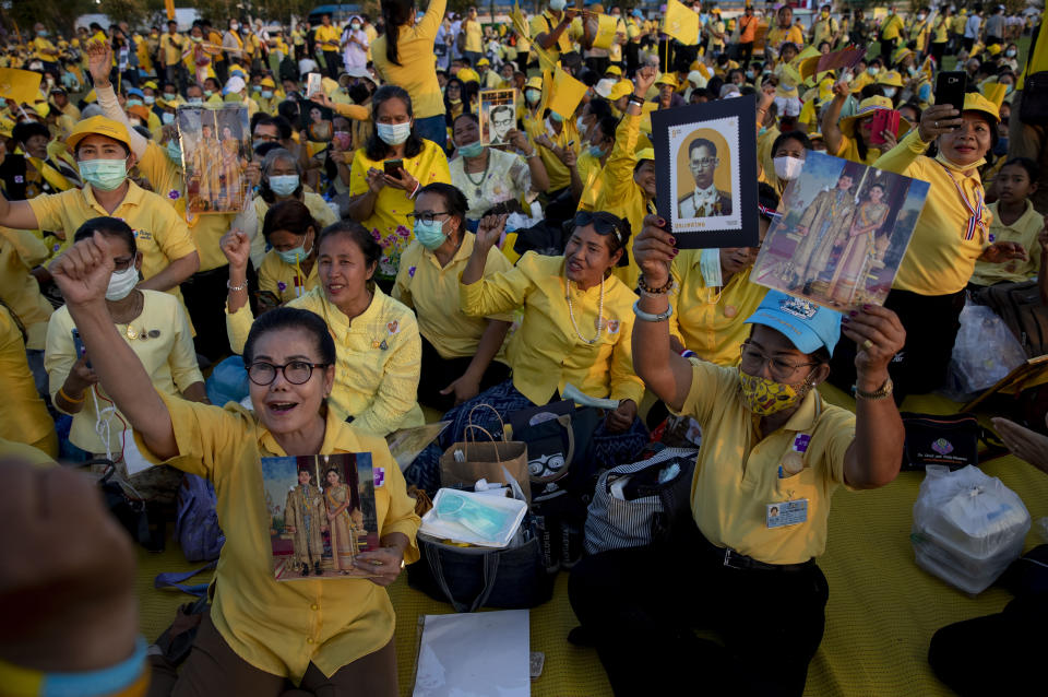 Supporters of Thai monarch display images of King Maha Vajiralongkorn, Queen Suthida and late King Bhumibol Adulyadej ahead of the arrival of king and queen to participate in a candle lighting ceremony to mark birth anniversary of late King Bhumibol Adulyadej at Sanam Luang ceremonial ground in Bangkok, Thailand, Saturday, Dec. 5, 2020. (AP Photo/Gemunu Amarasinghe)