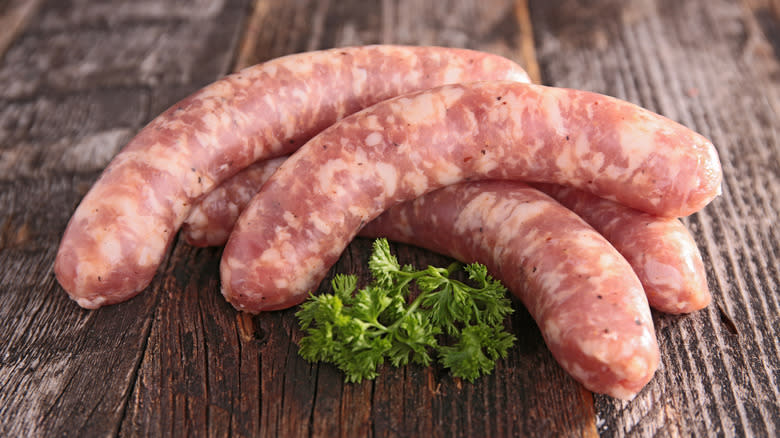 Raw sausages on wooden board