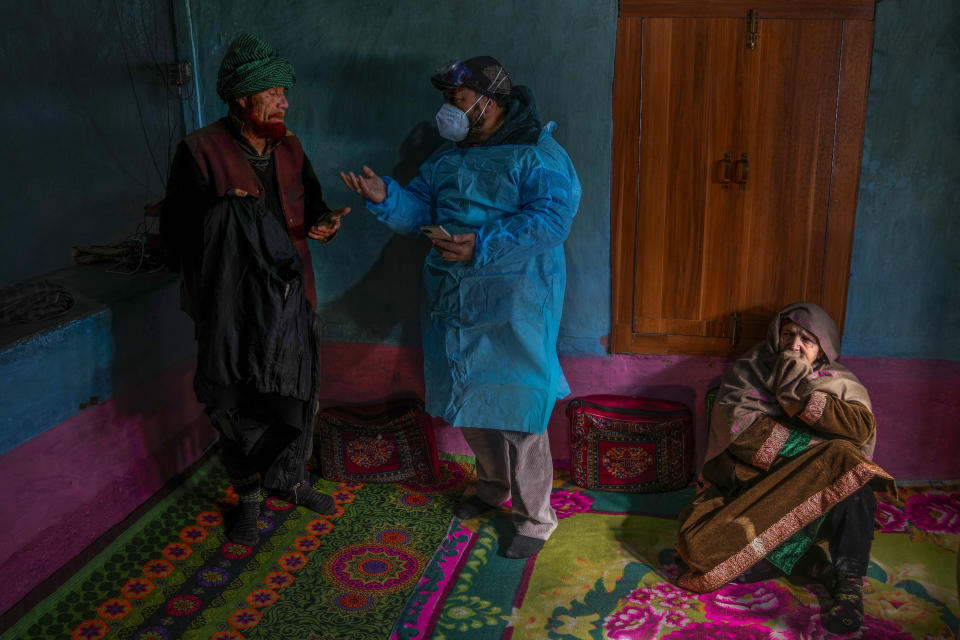 Jaffer Ali, a healthcare worker, talks to Ghulam Yousaf Mir after administering him a booster dose of the Covishield vaccine as her relative Naseera Begum, who refused to get vaccinated, watches inside their house during a COVID-19 vaccination drive in Gagangeer, northeast of Srinagar, Indian controlled Kashmir, Jan. 12, 2022. (AP Photo/Dar Yasin)