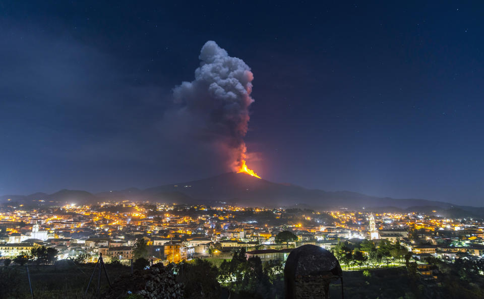 Flames and smoke billowing from a crater, as seen from the southern side of the Mt Etna volcano, tower over the city of Pedara, Sicily, Wednesday night, Feb. 24, 2021. Europe's most active volcano has been steadily erupting since last week, belching smoke, ash, and fountains of red-hot lava. (AP Photo/Salvatore Allegra)