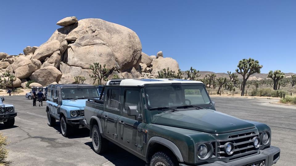 a group of cars parked on a road with rocks in the background