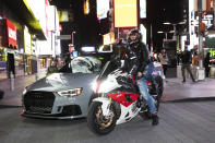 In this Saturday, May 2, 2020 photo, a sports car and motorcyclists are part of the scene in New York's Times Square during the coronavirus pandemic. Car mavens and motorcyclists normally wouldn't dare rev their engines in Midtown, but now they're eagerly driving into the city to take photos and show off for sparse crowds walking through the commercial hub. (AP Photo/Mark Lennihan)