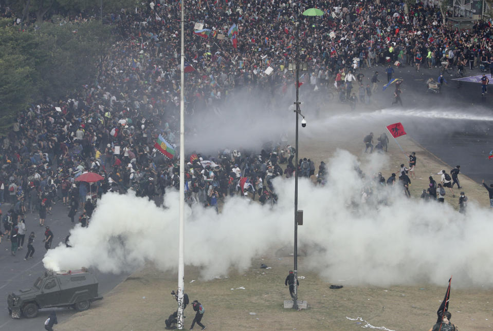 Police spray tear gas and water during an anti-government protest in Santiago, Chile, Monday, Nov. 4, 2019. Chile has been facing weeks of unrest, triggered by a relatively minor increase in subway fares. The protests have shaken a nation noted for economic stability over the past decades, which has seen steadily declining poverty despite persistent high rates of inequality. (AP Photo/Esteban Felix)