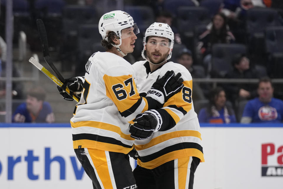 Pittsburgh Penguins' Rickard Rakell, left, celebrates his goal against the New York Islanders with Michael Bunting during the first period of an NHL hockey game Wednesday, April 17, 2024, in Elmont, N.Y. (AP Photo/Seth Wenig)