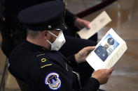 A U.S. Capitol Police officer looks at the program for U.S. Capitol Police officer William "Billy" Evans as he lies in honor during a ceremony at the Capitol in Washington, Tuesday, April 13, 2021. (Amr Alfiky/The New York Times via AP, Pool)