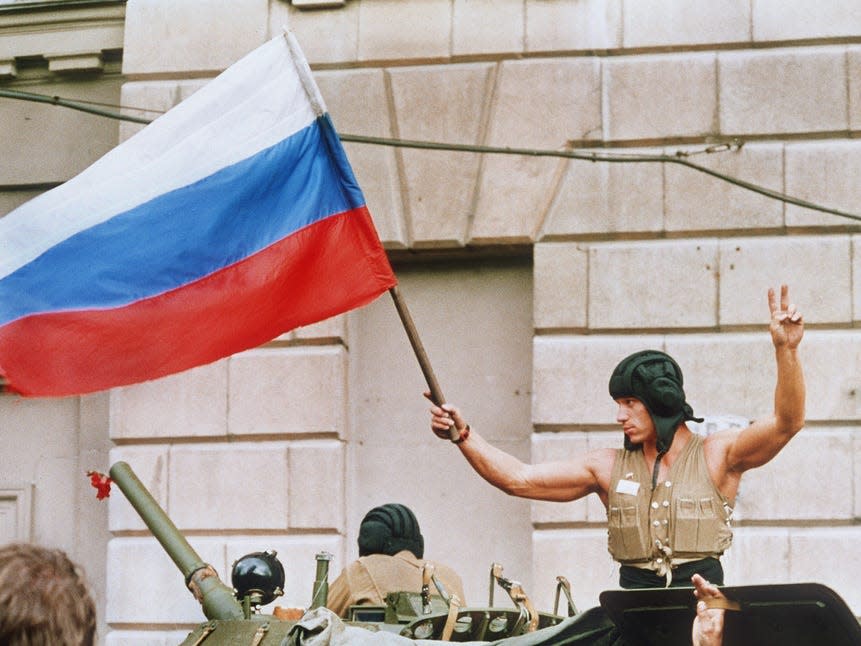 A soldier waves a Russian flag from the top of his tank as armored units leave their positions in Moscow following the collapse of the military coup against president Gorbatchev in 1991.