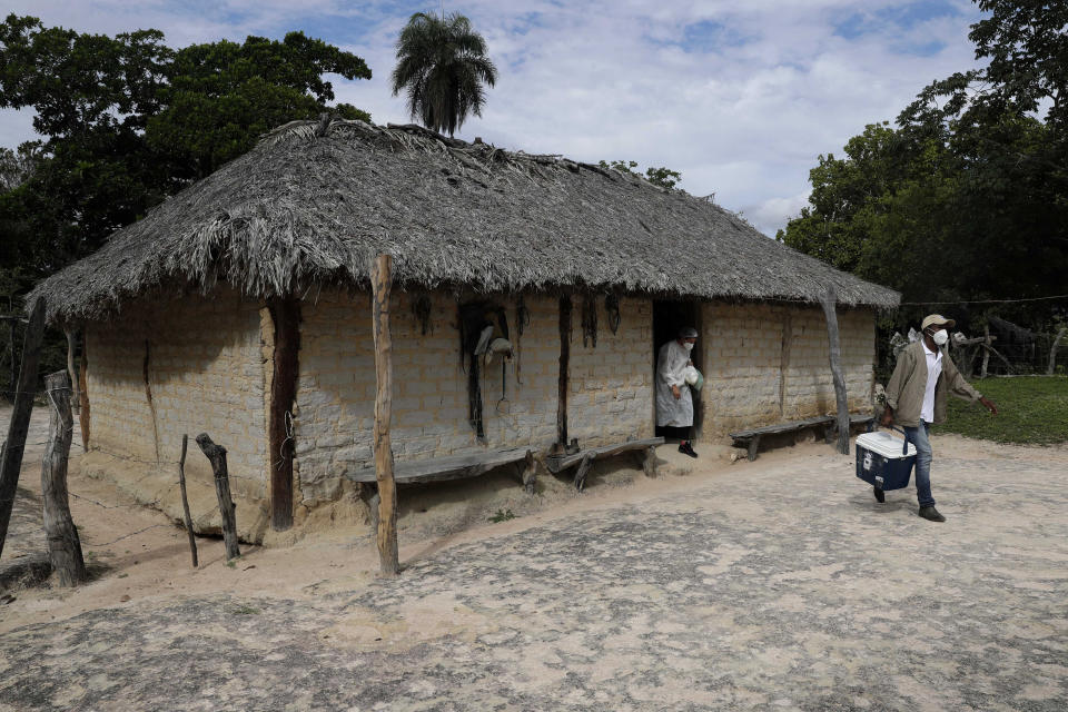 FILE - In this March 16, 2021 file photo, healthcare workers leave a home after vaccinating residents with the Sinovac COVID-19 vaccine, during a house-to-house vaccination campaign in the Kalunga Vao de Almas quilombo on the outskirts of Cavalcante, Goias state, Brazil. The country's vast size and deficient infrastructure make getting coronavirus vaccines to far-flung communities of Indigenous peoples and descendants of slaves a particularly daunting endeavor. (AP Photo/Eraldo Peres, File)